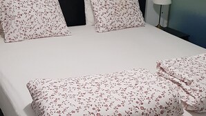A neatly made bed with floral-patterned pillows and a black headboard. - sam29 3-Bed Villa in Monolithos (Monolithos)