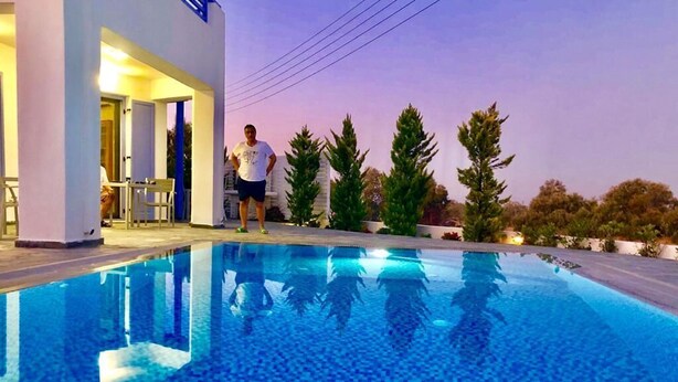 A swimming pool with a tiled floor and a person standing by the poolside. - sam29 3-Bed Villa in Monolithos (Monolithos)
