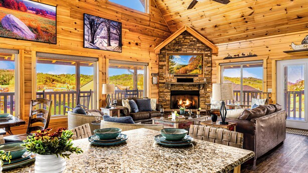 A spacious living area with a stone fireplace, wooden ceiling, and large windows offering scenic views. - Read Our Reviews! Indoor Pool + Outdoor Pool + View (Sevierville)
