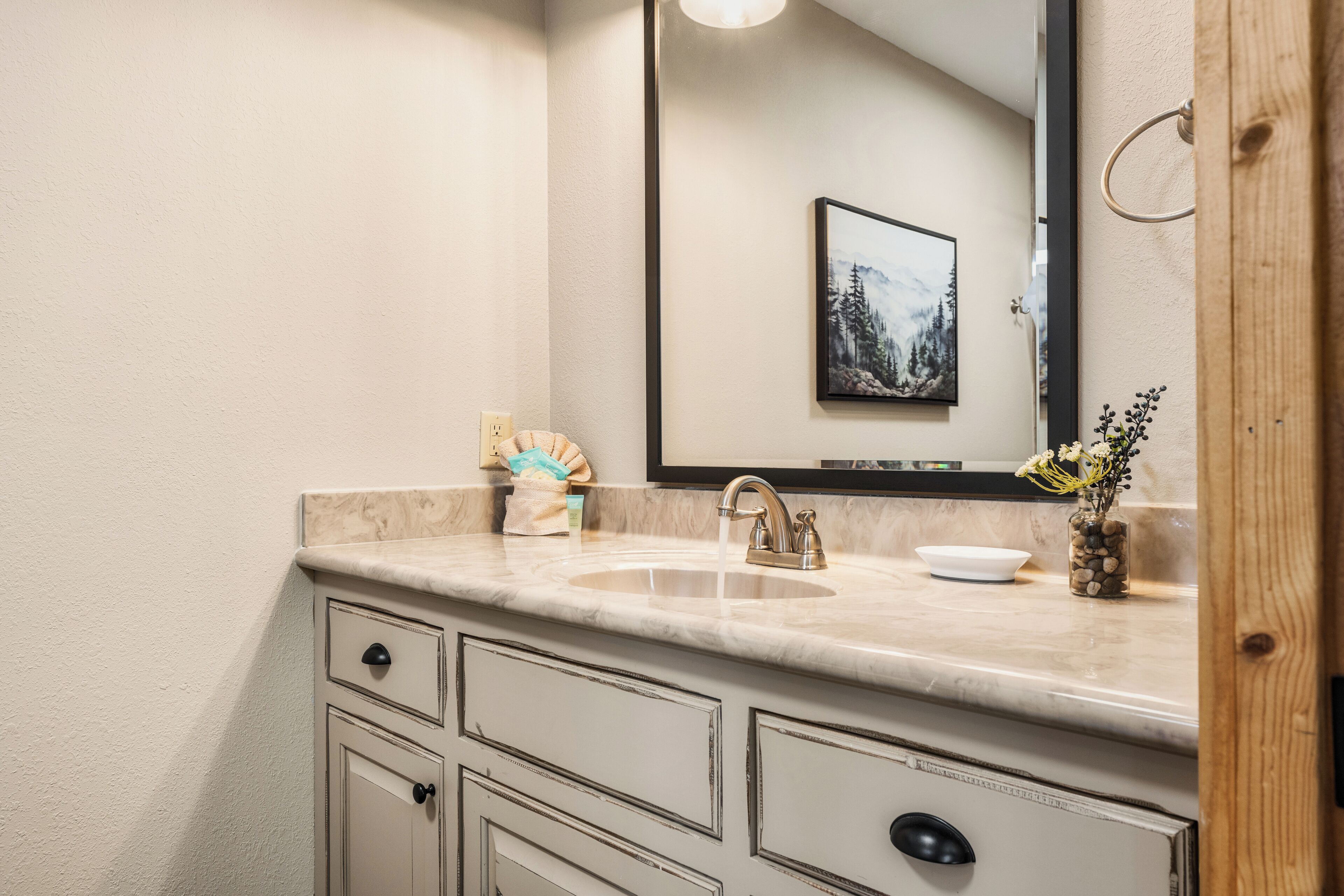 A bathroom with a sink, mirror, and a framed picture on the wall.