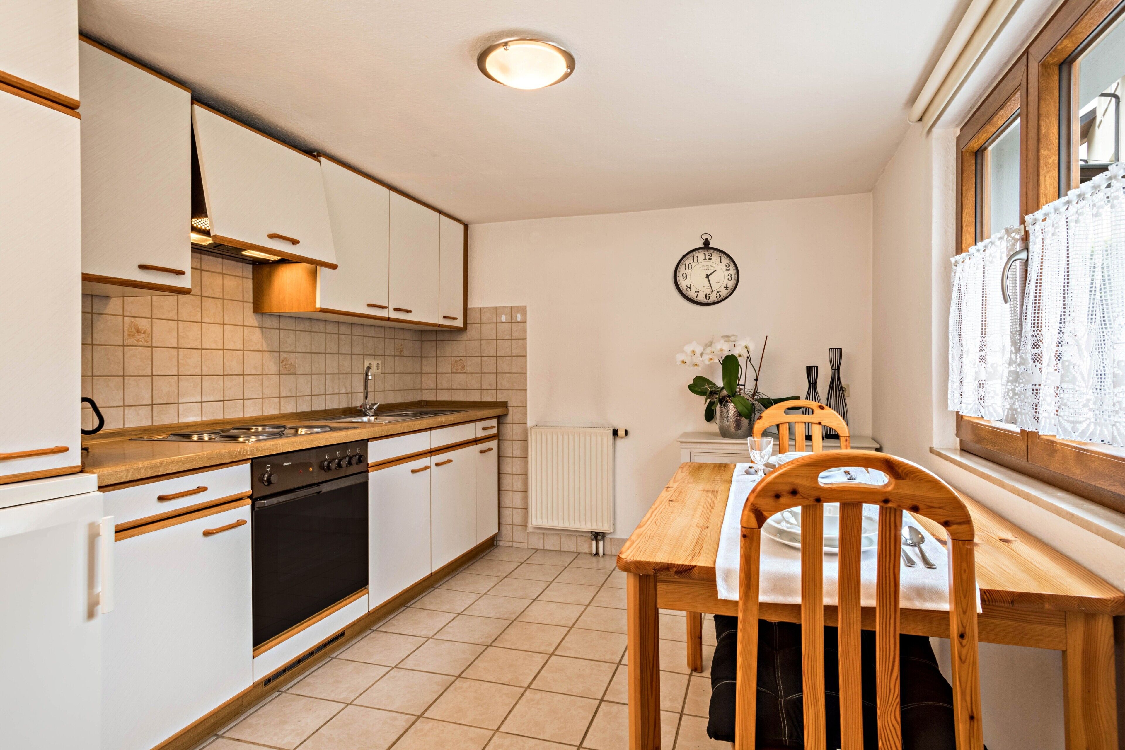A kitchen with white cabinets, a wooden countertop, a stove, and a dining table with chairs.