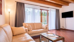 Un salon avec un canapé beige, une table basse en verre et un téléviseur à écran plat fixé au mur.