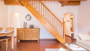 Un escalier en bois, une table à manger avec des chaises, un canapé et une horloge murale.
