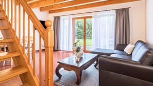 Un escalier en bois, un canapé, une table basse et une vue sur l’extérieur par une porte vitrée.
