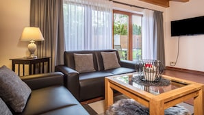 Una sala de estar con un sofá, una mesa de centro, una lámpara, un televisor y una ventana con cortinas.