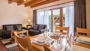Un comedor con una mesa de madera preparada para cuatro personas, un sofá y una lámpara.