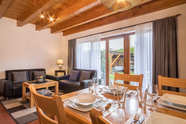 A dining area with a wooden table set for four, a sofa, and a lamp.
