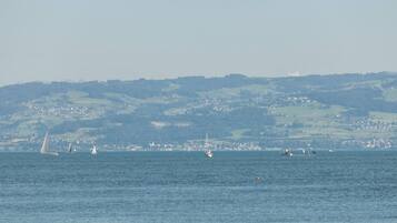 Une vue sur la côte, avec des voiliers sur l’eau et une ville qui se dessine à l’horizon.