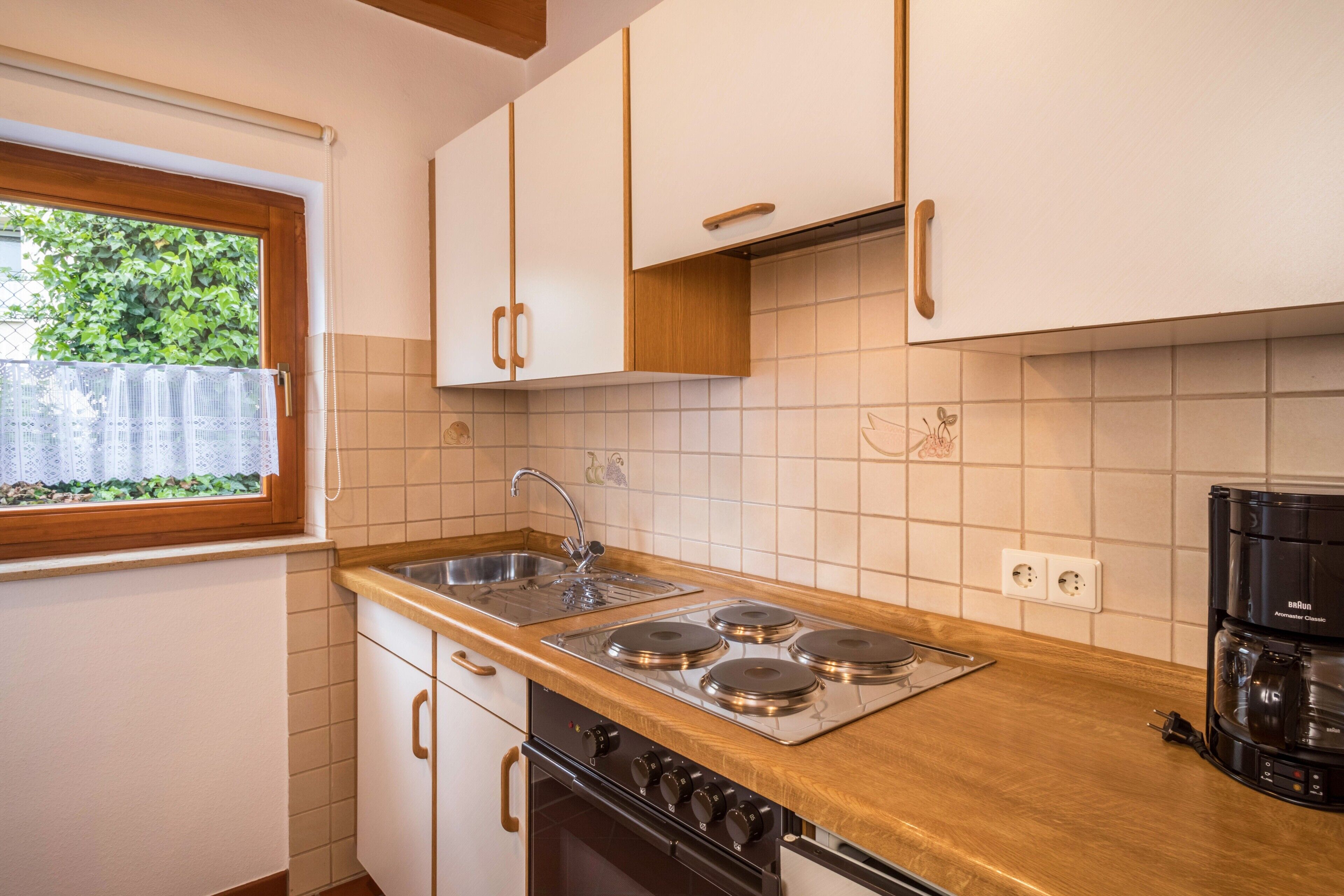 A kitchen with a wooden countertop, stainless steel sink, and a coffee maker.