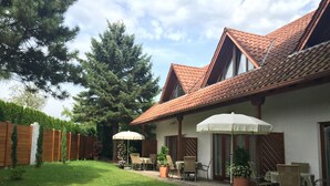 Una casa con techo de tejas, patio cercado y mobiliario exterior.