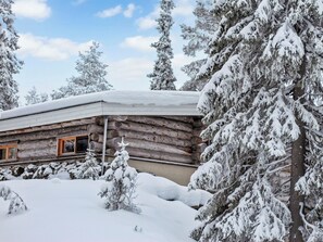 Eine Blockhütte, umgeben von schneebedeckten Bäumen.