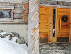 A wooden cabin with a stone-tiled entrance and a wooden door with a wreath.