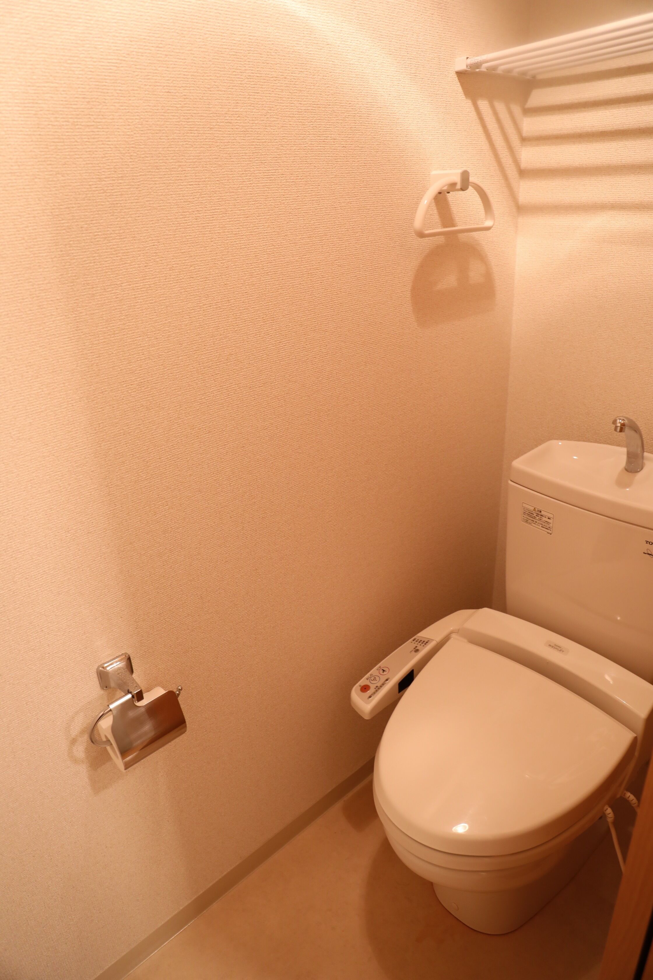 A small, modern bathroom with a toilet, a sink, and a towel rack.