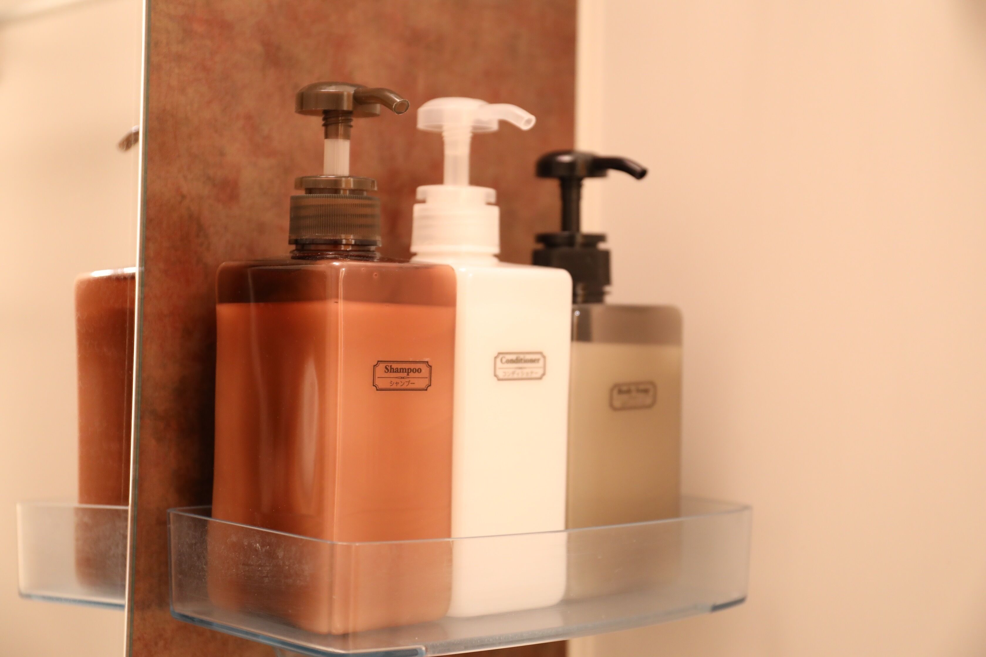 Estante de baño con tres botellas de champú y acondicionador.