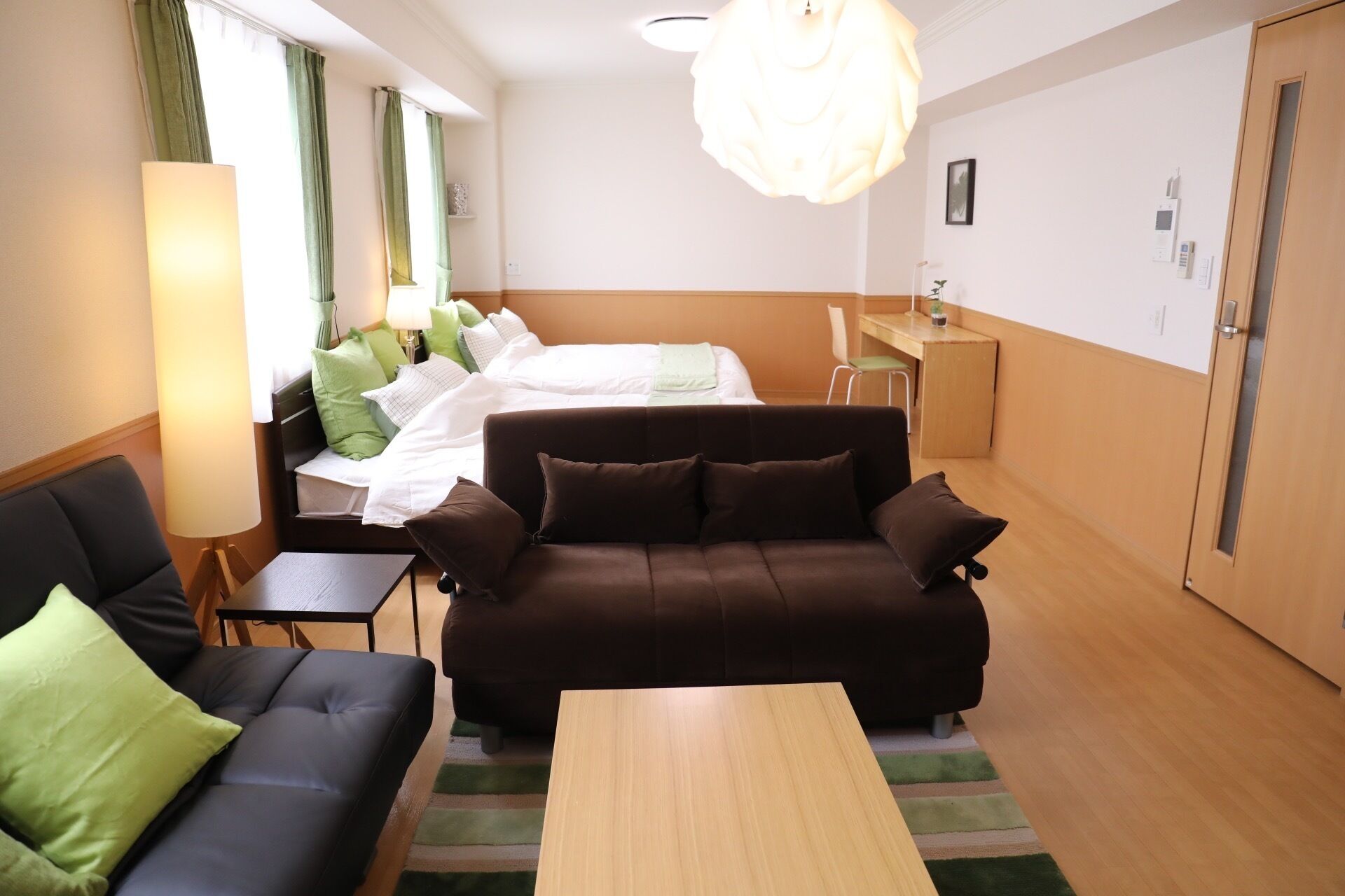 A hotel room with a bed, a sofa, a coffee table, a desk, and a chair.