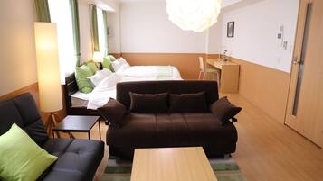 A hotel room with a bed, a sofa, a coffee table, a desk, and a chair.