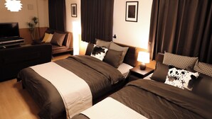 Ett hotellrum med två sängar, en soffa, en tv och en lampa.