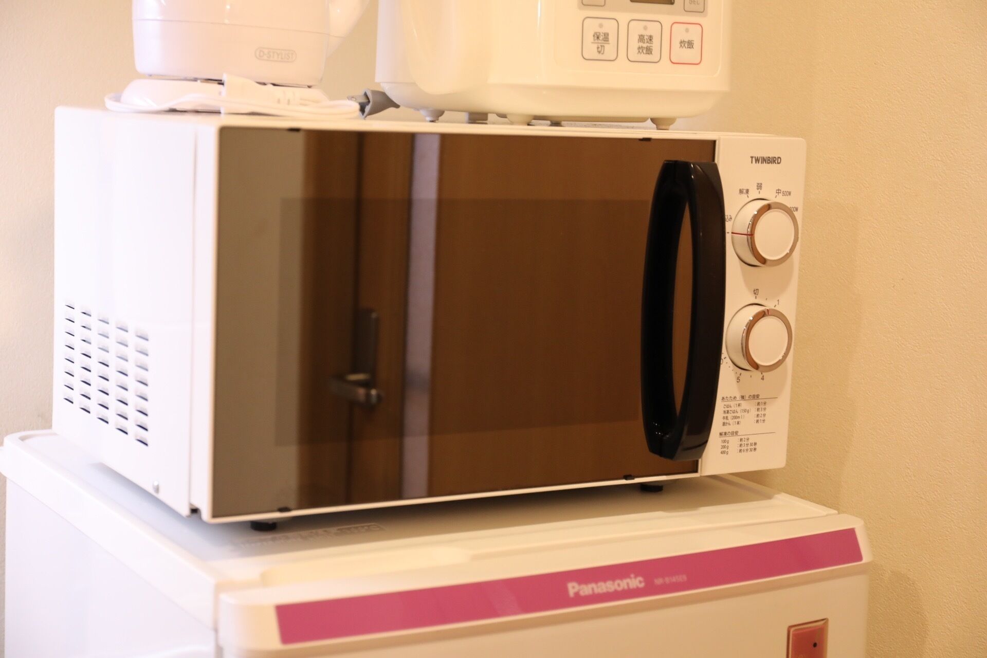 A Panasonic microwave oven with a digital display and control panel, placed on top of a white appliance.