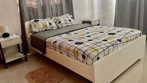 A bedroom with a bed, nightstands, a lamp, and a rug.