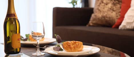 Una mesa de comedor con una botella de vino, una copa y un plato con comida.