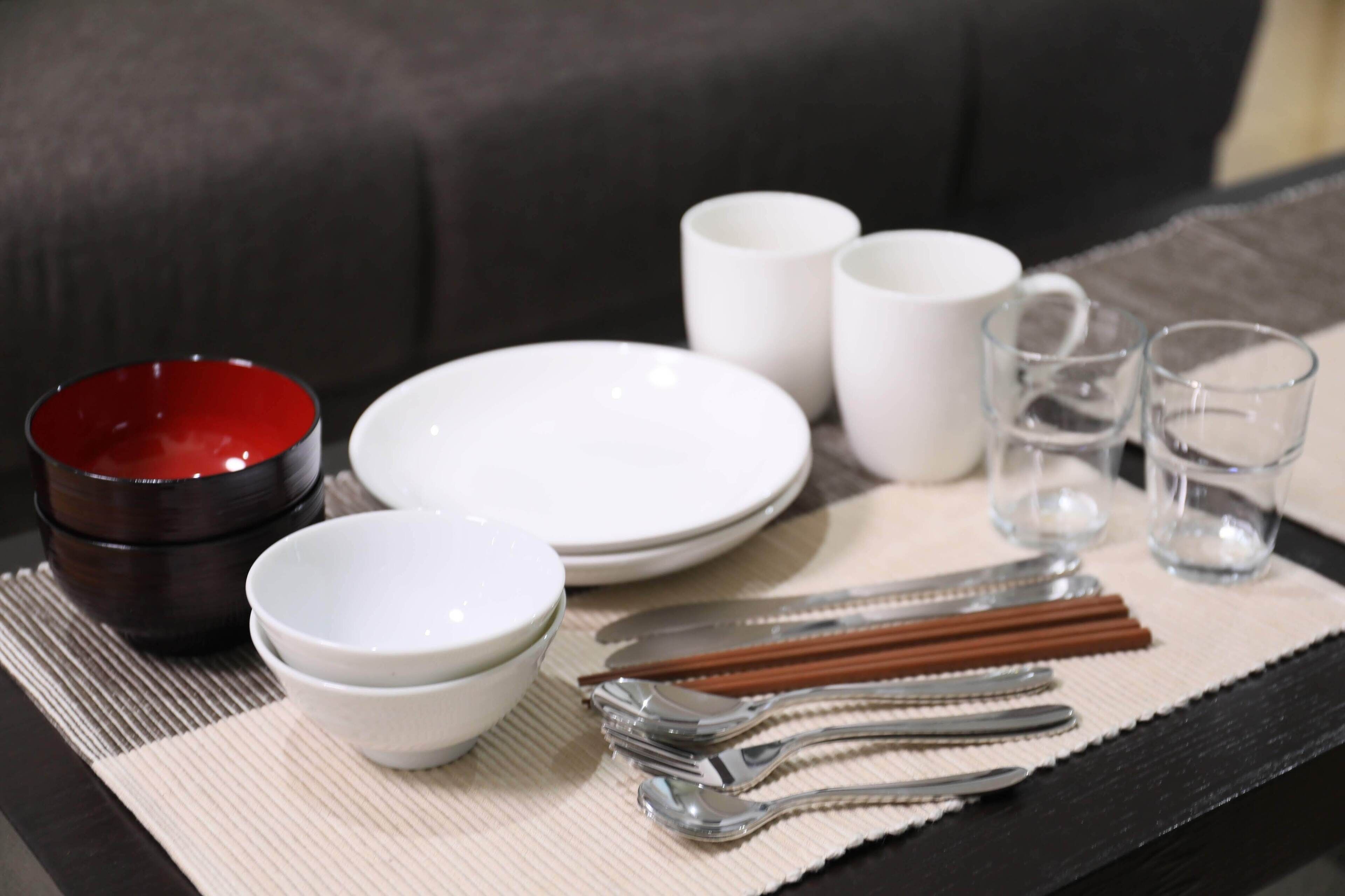 A dining setup with bowls, plates, chopsticks, and glasses on a placemat.
