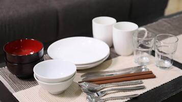 A dining setup with bowls, plates, chopsticks, and glasses on a placemat.