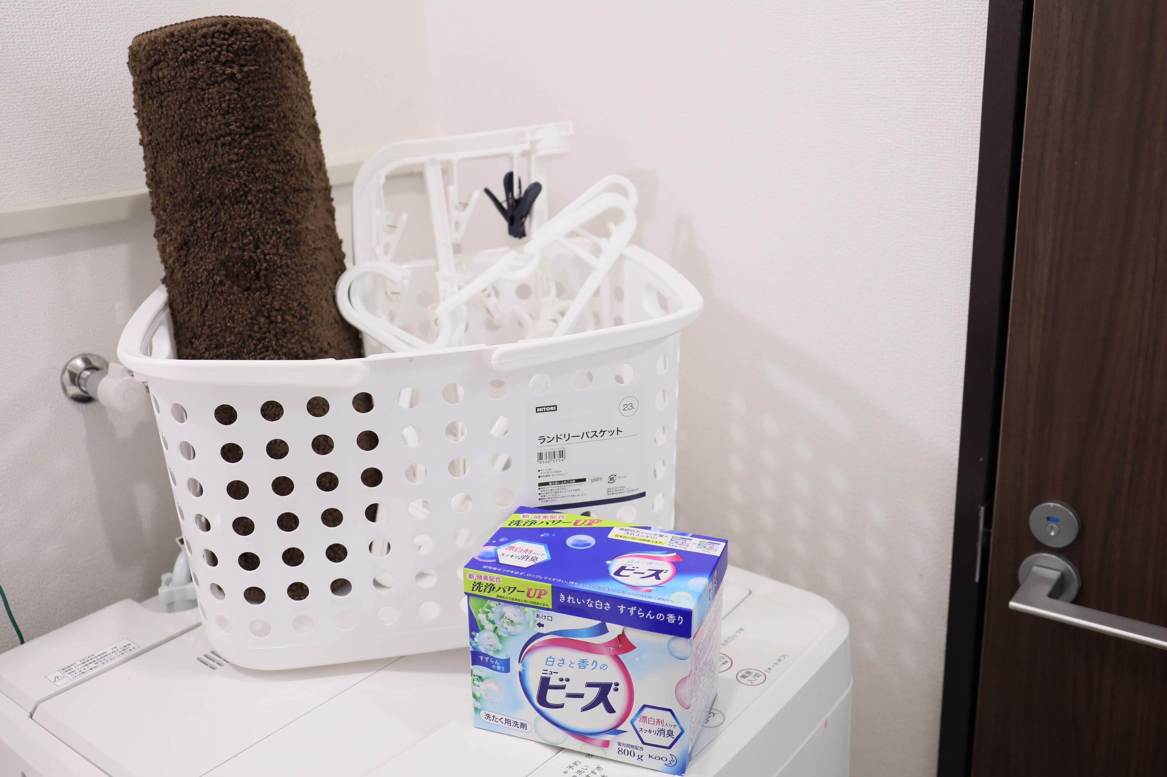 A laundry basket with a towel and a box of laundry detergent on a white washing machine.