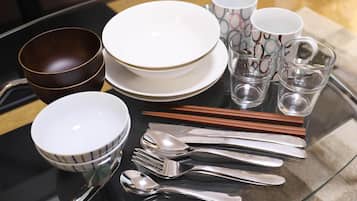 A table set with white plates, bowls, and cutlery, along with patterned cups and shot glasses.