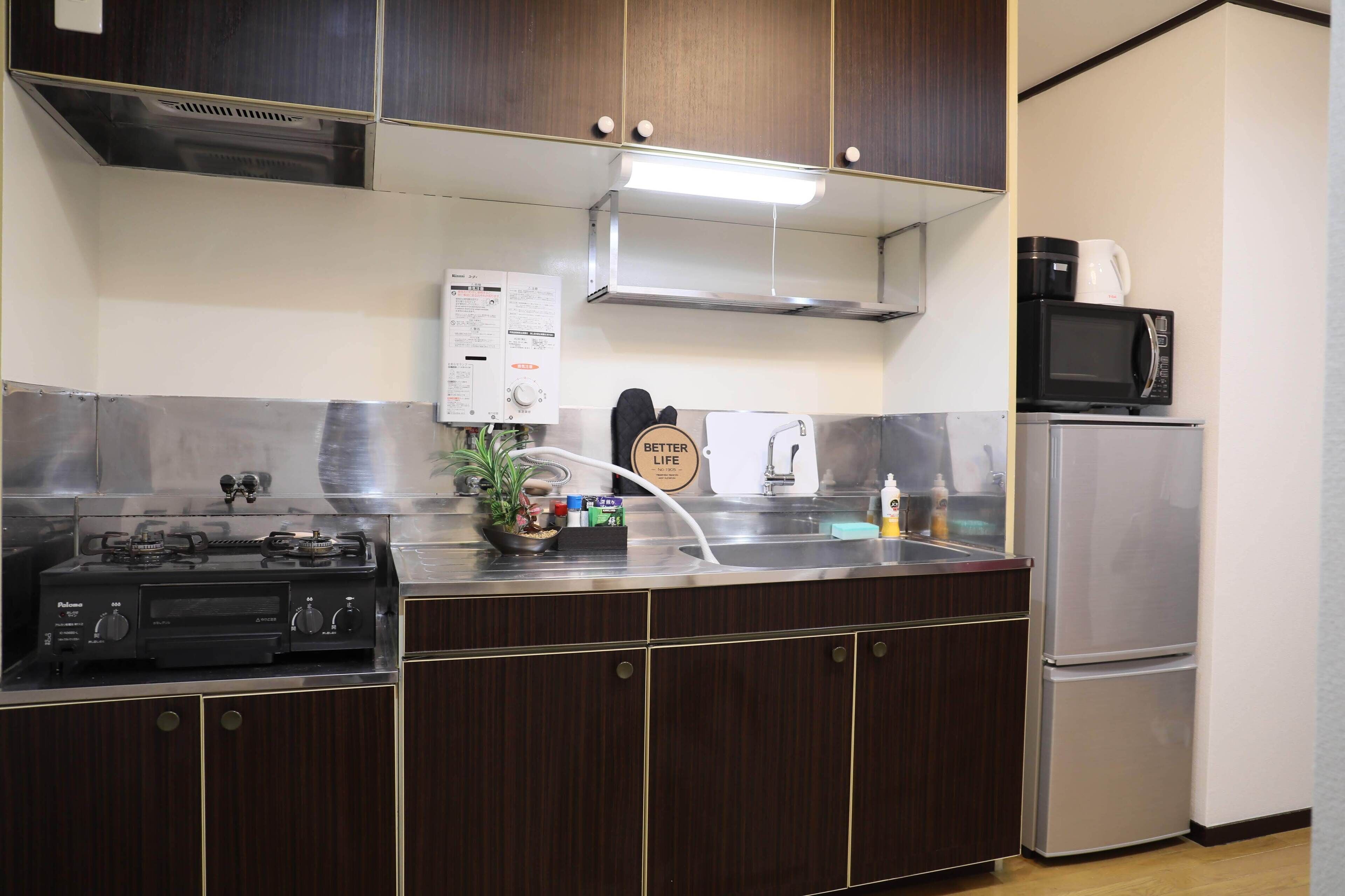A kitchen with dark wood cabinets, stainless steel appliances, a stove, a microwave, and a refrigerator.