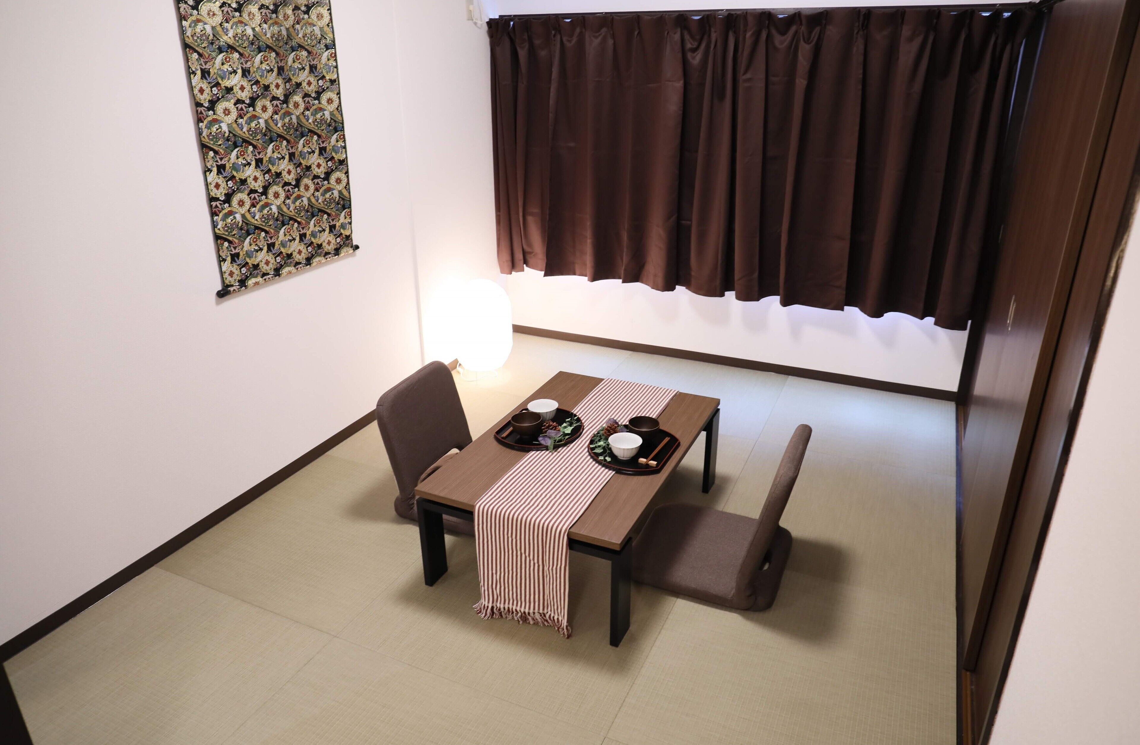 A dining area with a table set for two, a chair, a bench, and a wall-mounted light fixture.