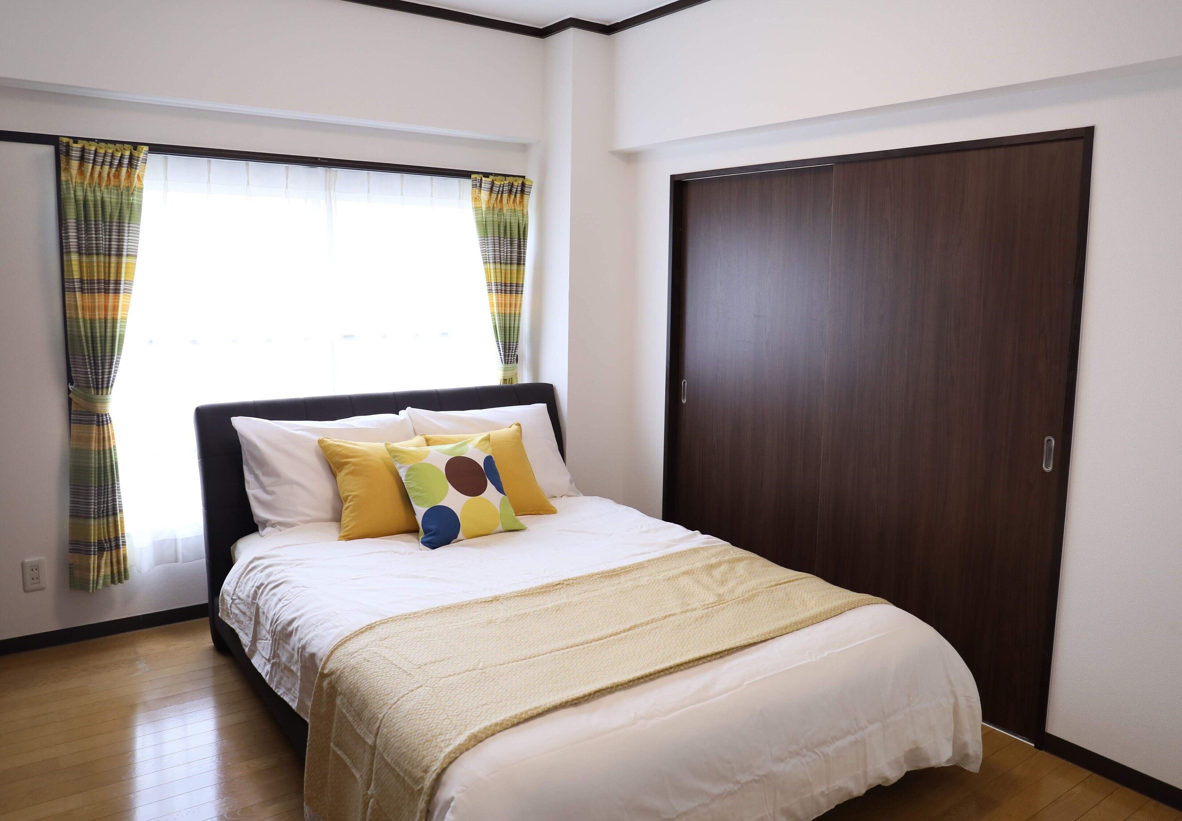 Una camera da letto ordinata con un letto, tende e un armadio.