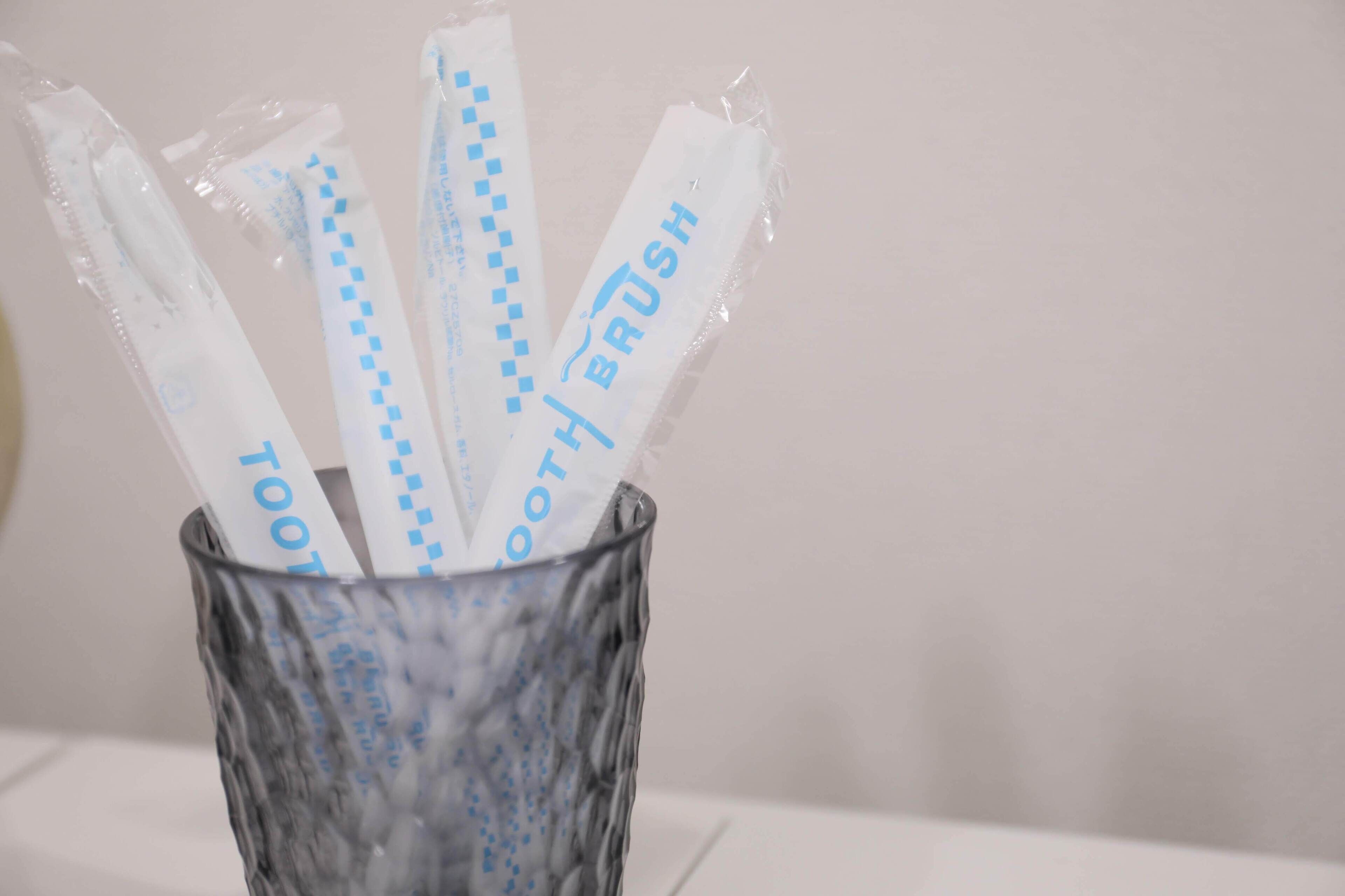 A glass container holding several toothbrushes with blue packaging.