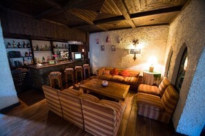 A cozy bar area with wooden furniture, a stone wall, and a bar counter with various bottles. - Hostería del Viejo Molino (San Carlos de Bariloche)