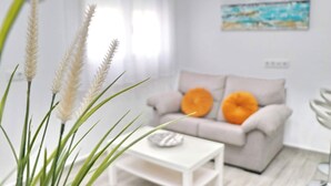 A modern living room with a white sofa, a small white table, and a vase with white flowers. - Apartment Isabella Vejer (Vejer de la Frontera)