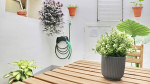 A wooden table with a potted plant, a hanging garden hose, and a window with a plant on the sill. - Apartment Isabella Vejer (Vejer de la Frontera)