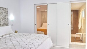 A bedroom with a bed, a wardrobe, and a bathroom visible through an open door. - Apartment Isabella Vejer (Vejer de la Frontera)