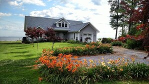 Une maison avec une pelouse bien entretenue, une allée et une variété de fleurs colorées au premier plan.