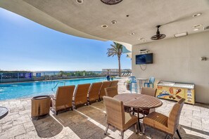 A poolside area with wicker chairs and a table, a pool, and a food service station. - *Oct 28 - Nov 5th open! * Beautiful condo! (Panama City Beach)