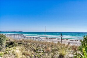 A beach with a wooden walkway leading to the shore, a pier in the distance, and ocean waves. - *Oct 28 - Nov 5th open! * Beautiful condo! (Panama City Beach)