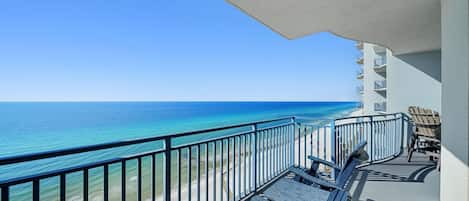 Ein Balkon mit Blick auf den Ozean, ein Pool und ein mehrstöckiges Gebäude.