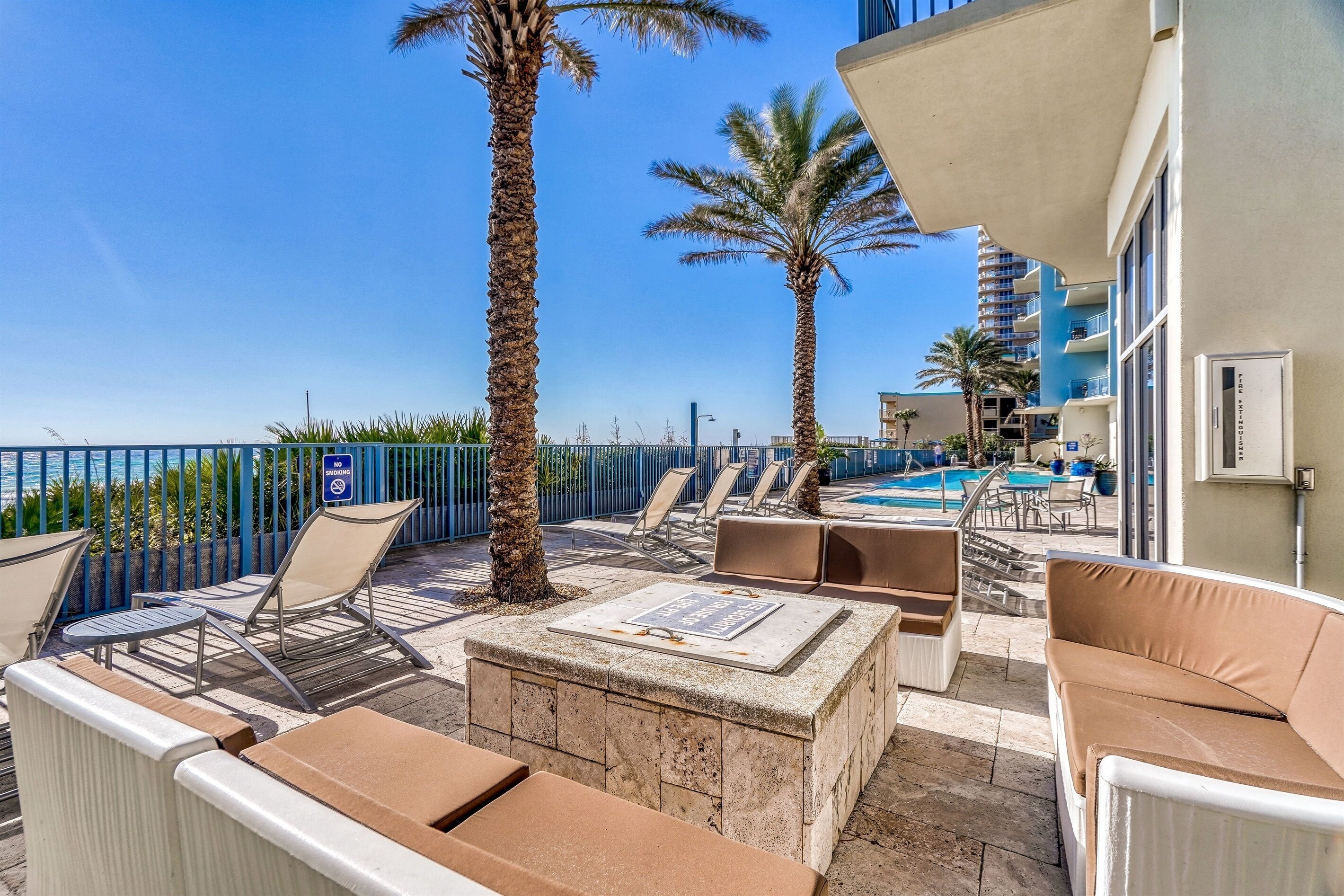 A rooftop terrace with lounge chairs, a pool, and palm trees.