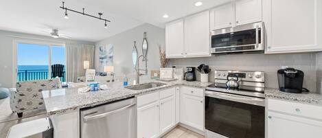 A modern kitchen with white cabinets, a stainless steel stove, a microwave, and a coffee maker.