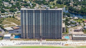 Ein hoch aufragendes Hotel mit mehreren Stockwerken, einem Schwimmbad und einer Strandlage.