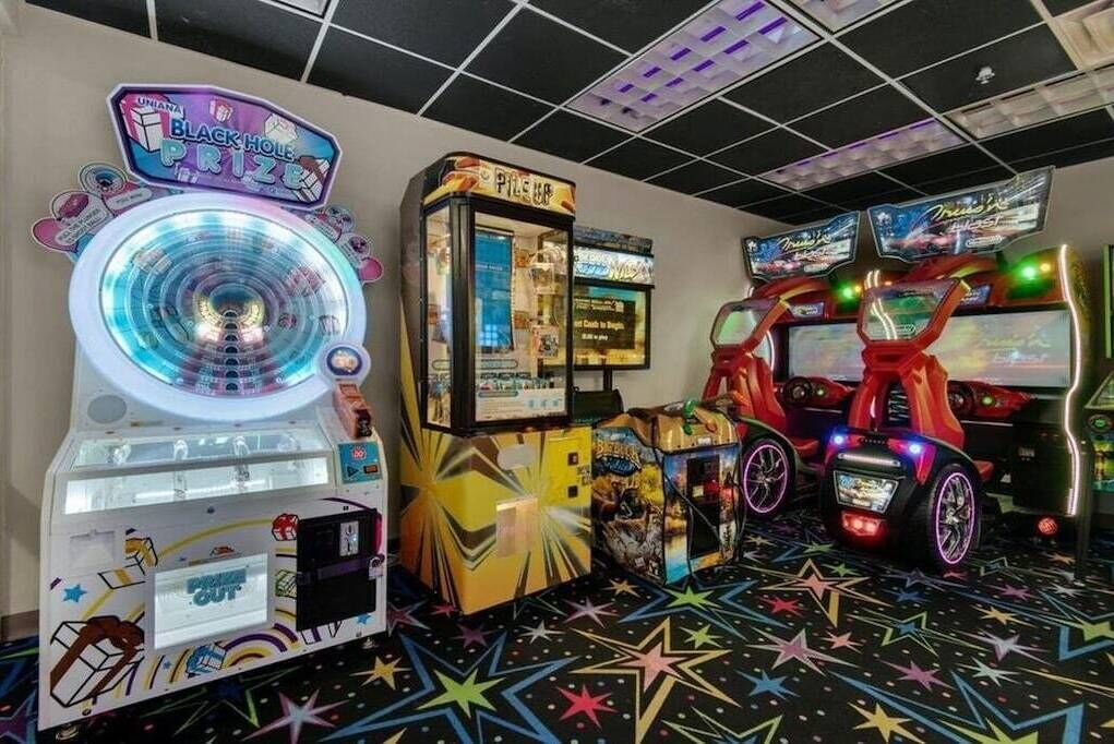 Ein Spielhallenambiente mit verschiedenen Automaten, darunter eine Gewinnspielwalze und Rennspiele.