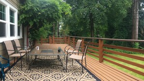 Un patio con una mesa y sillas, una cerca de madera y vistas a árboles.