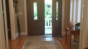 Un pasillo con suelo de madera, una alfombra y una puerta que da a un balcón.