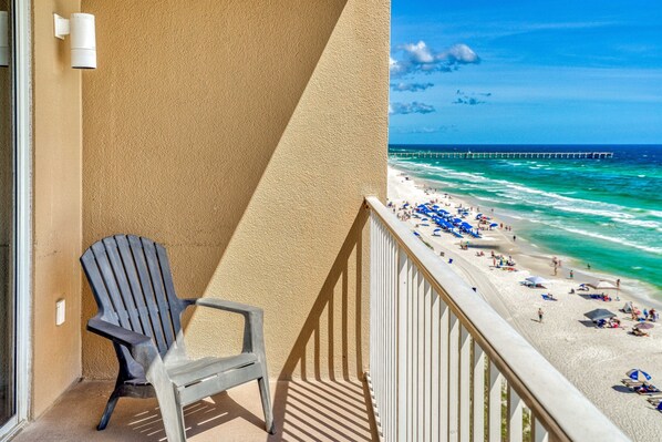 A balcony with a view of a beach, a pier, and a chair. - Oct 19 - 26th Open! Gulf Front Master! (Panama City Beach)