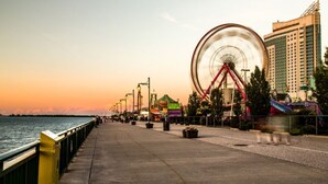 A waterfront promenade with a Ferris wheel, a roller coaster, and a tall building in the background. - Quiet affordable 2 Bed 1 bath suite in a single family detached house (Windsor)