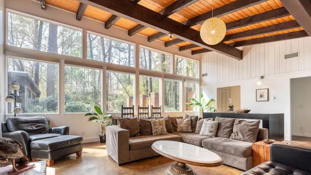 A spacious living room with large windows, a wooden ceiling, and a mix of sofas and a coffee table. - Buckhead Battle House - an MCM architectural masterpiece (Atlanta)