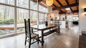 A spacious room with a large dining table, chairs, and a hanging light fixture. - Buckhead Battle House - an MCM architectural masterpiece (Atlanta)
